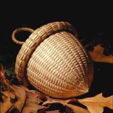 Acorn sweetgrass basket with brown ash rims and handles.