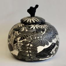 The fitted lid of this jar has a stained grapevine wood handle. The images on the surface of the pot were created using sgraffito and depict flowers  insects  birds and a frog.