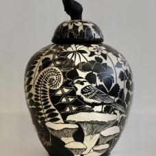 The lid of this jar is edged with woven pine needles and has a stained grapevine wood handle. The images on the surface of the pot were created using sgraffito and depict flowers  insects  birds and ferns.