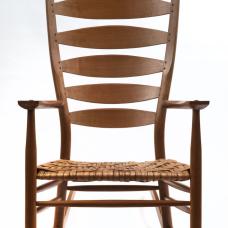 Walnut rocking chair featuring steam bent components  hand-shaped surfaces and a woven hickory bark seat. Oil and wax finish.