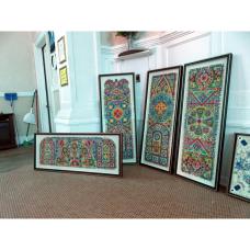 Four Colorful geometric pieces connected and embellished with thread, leaning against a wall, the height of half a doorway.