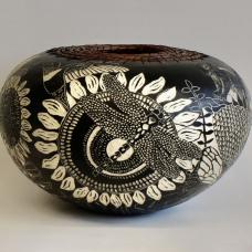 The images on the surface of the pot were created using sgraffito and depict flowers  insects  birds and a chipmunk. The top is edged with woven pine needles.