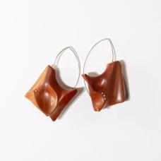 Hand shaped and polished Pink Ivory wood with Argentium Silver details and ear wires. A locking system is employed to bond the metal and wood. A keyhole system is drilled within the wood and the metal is knurled before epoxying wood and metal together.